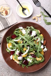 Photo of Tasty salad with arugula, cheese, peach, beetroot and nuts on grey table, flat lay