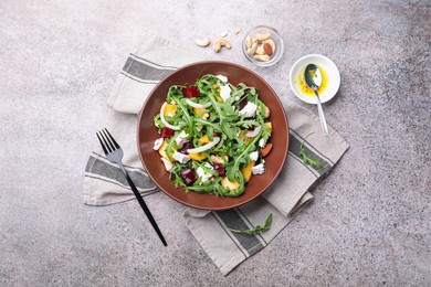 Photo of Tasty salad with arugula, cheese, peach, beetroot and nuts on grey table, flat lay