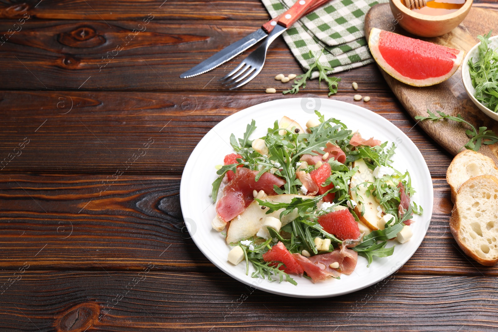 Tasty salad with arugula and prosciutto served on wooden table, closeup. Space for text Photo of Tasty salad with arugula and prosciutto served on wooden table, closeup. Space for text