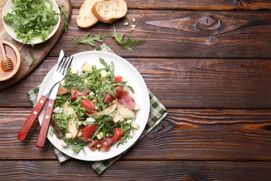 Photo of Tasty salad with arugula and prosciutto served on wooden table, flat lay. Space for text
