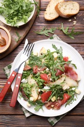 Photo of Tasty salad with arugula and prosciutto served on wooden table, flat lay