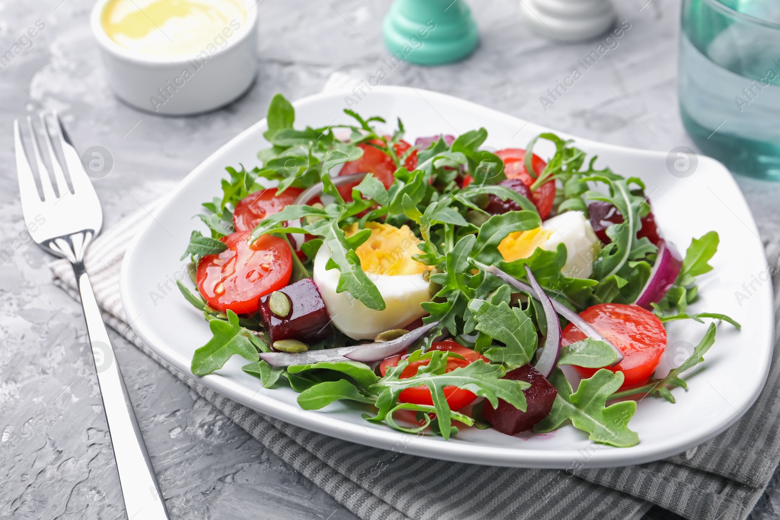 Tasty salad with arugula, vegetables and egg served on grey table, closeup Photo of Tasty salad with arugula, vegetables and egg served on grey table, closeup
