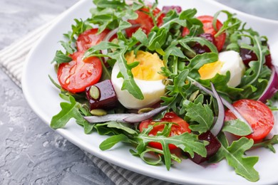 Photo of Tasty salad with arugula, vegetables, egg and seeds on grey table, closeup