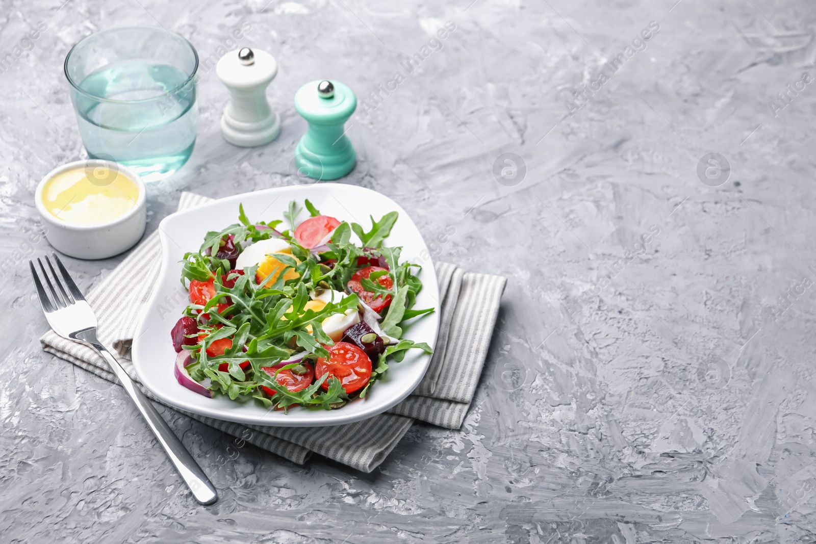 Tasty salad with arugula, vegetables and egg served on grey table, space for text Photo of Tasty salad with arugula, vegetables and egg served on grey table, space for text