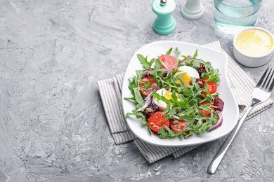 Photo of Tasty salad with arugula, vegetables and egg served on grey table, above view. Space for text