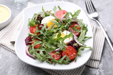 Photo of Tasty salad with arugula, vegetables, egg and seeds on grey table, closeup