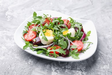 Photo of Tasty salad with arugula, vegetables, egg and seeds on grey table, closeup