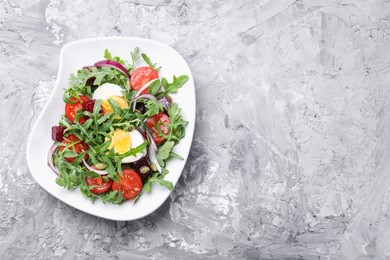 Photo of Tasty salad with arugula, vegetables, egg and seeds on grey table, top view. Space for text