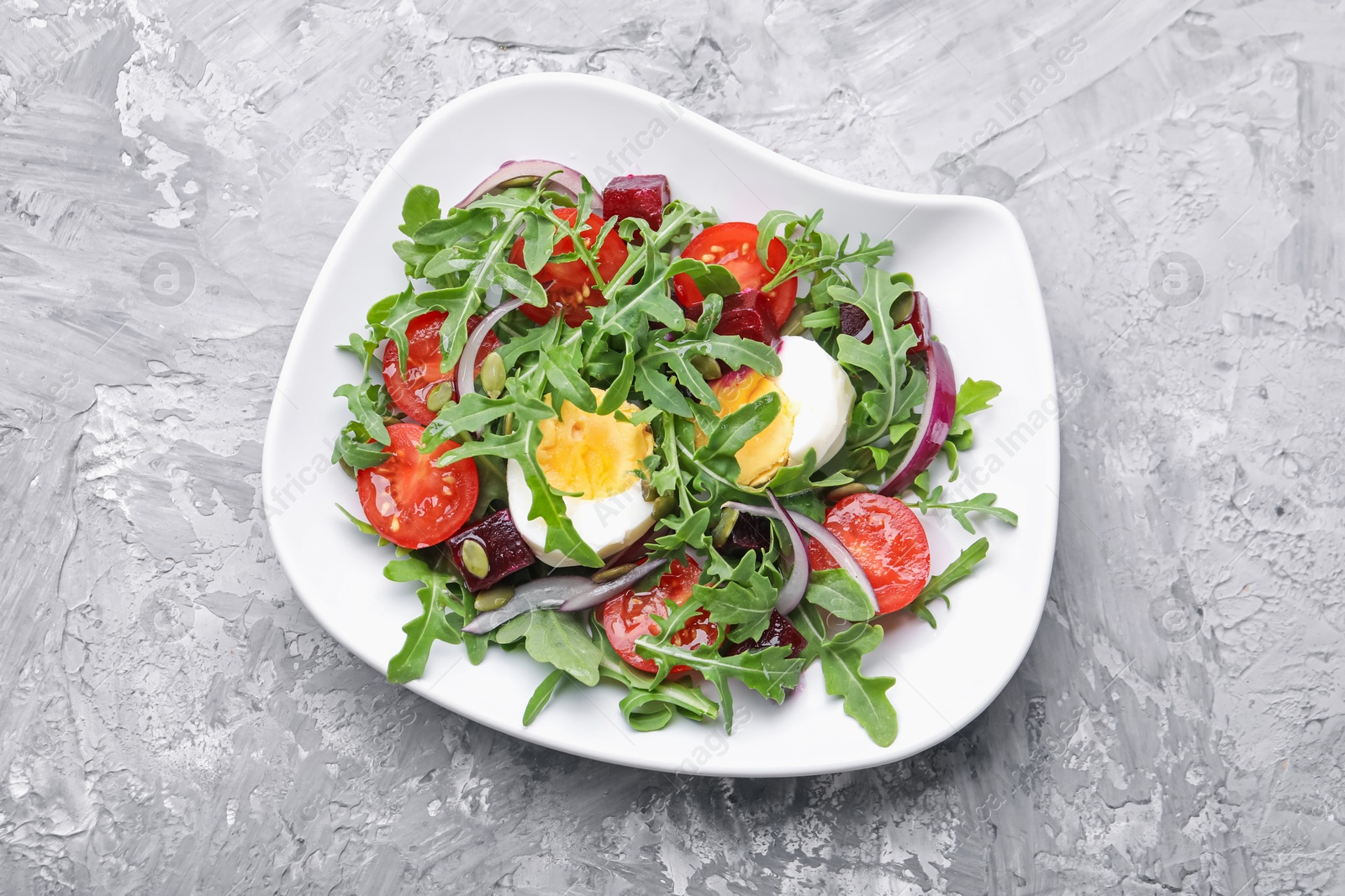 Tasty salad with arugula, vegetables, egg and seeds on grey table, top view Photo of Tasty salad with arugula, vegetables, egg and seeds on grey table, top view