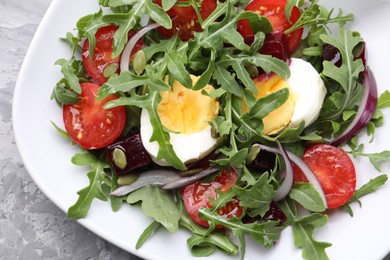 Photo of Tasty salad with arugula, vegetables, egg and seeds on grey table, top view