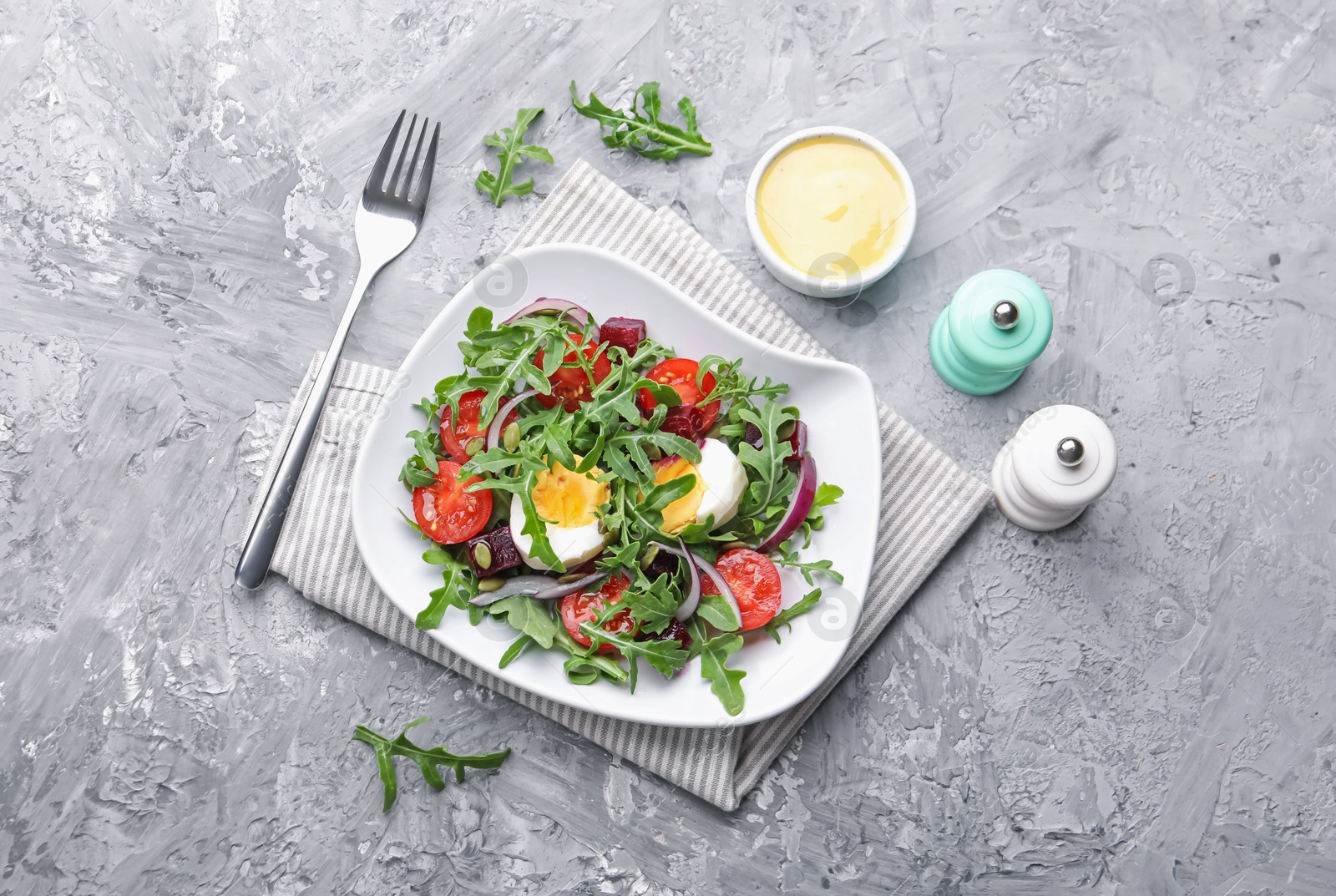 Tasty salad with arugula, vegetables and egg served on grey table, flat lay Photo of Tasty salad with arugula, vegetables and egg served on grey table, flat lay