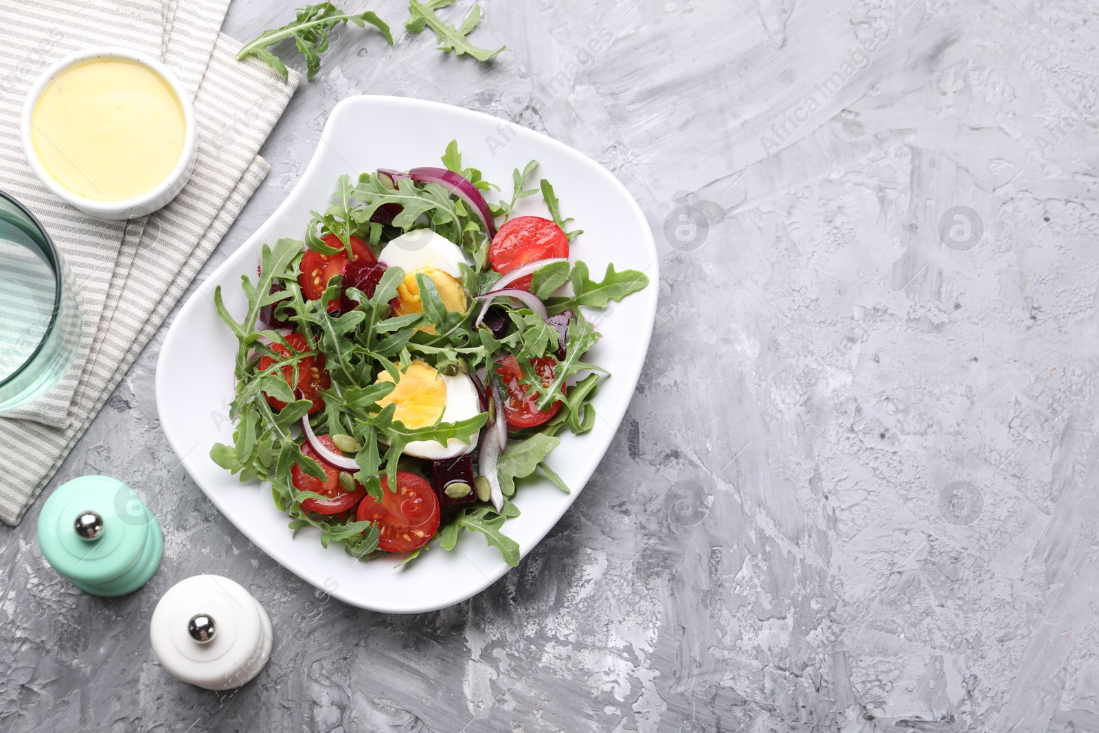 Tasty salad with arugula, vegetables and egg served on grey table, flat lay. Space for text Photo of Tasty salad with arugula, vegetables and egg served on grey table, flat lay. Space for text