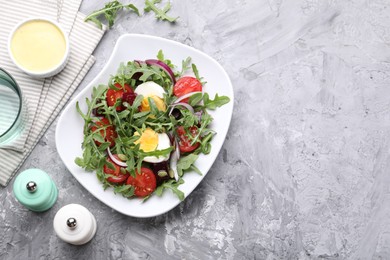 Photo of Tasty salad with arugula, vegetables and egg served on grey table, flat lay. Space for text