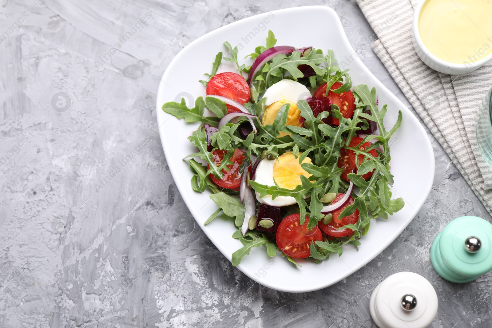 Tasty salad with arugula, vegetables and egg served on grey table, flat lay. Space for text Photo of Tasty salad with arugula, vegetables and egg served on grey table, flat lay. Space for text