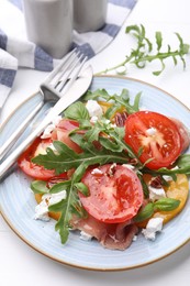 Photo of Tasty salad with arugula, cheese, tomatoes, nuts and prosciutto on white table, closeup