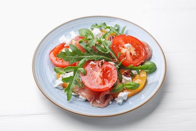 Photo of Tasty salad with arugula, cheese, tomatoes, nuts and prosciutto on white wooden table, closeup