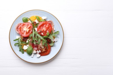 Photo of Tasty salad with arugula, cheese, tomatoes, nuts and prosciutto on white wooden table, top view. Space for text