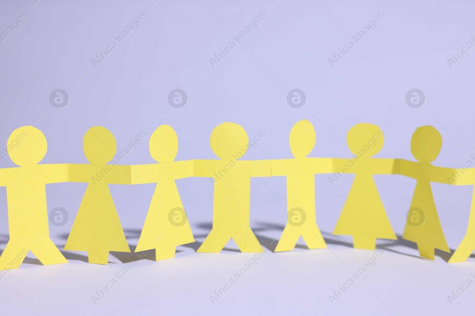 Paper figures of people holding hands on white background, closeup Photo of Paper figures of people holding hands on white background, closeup