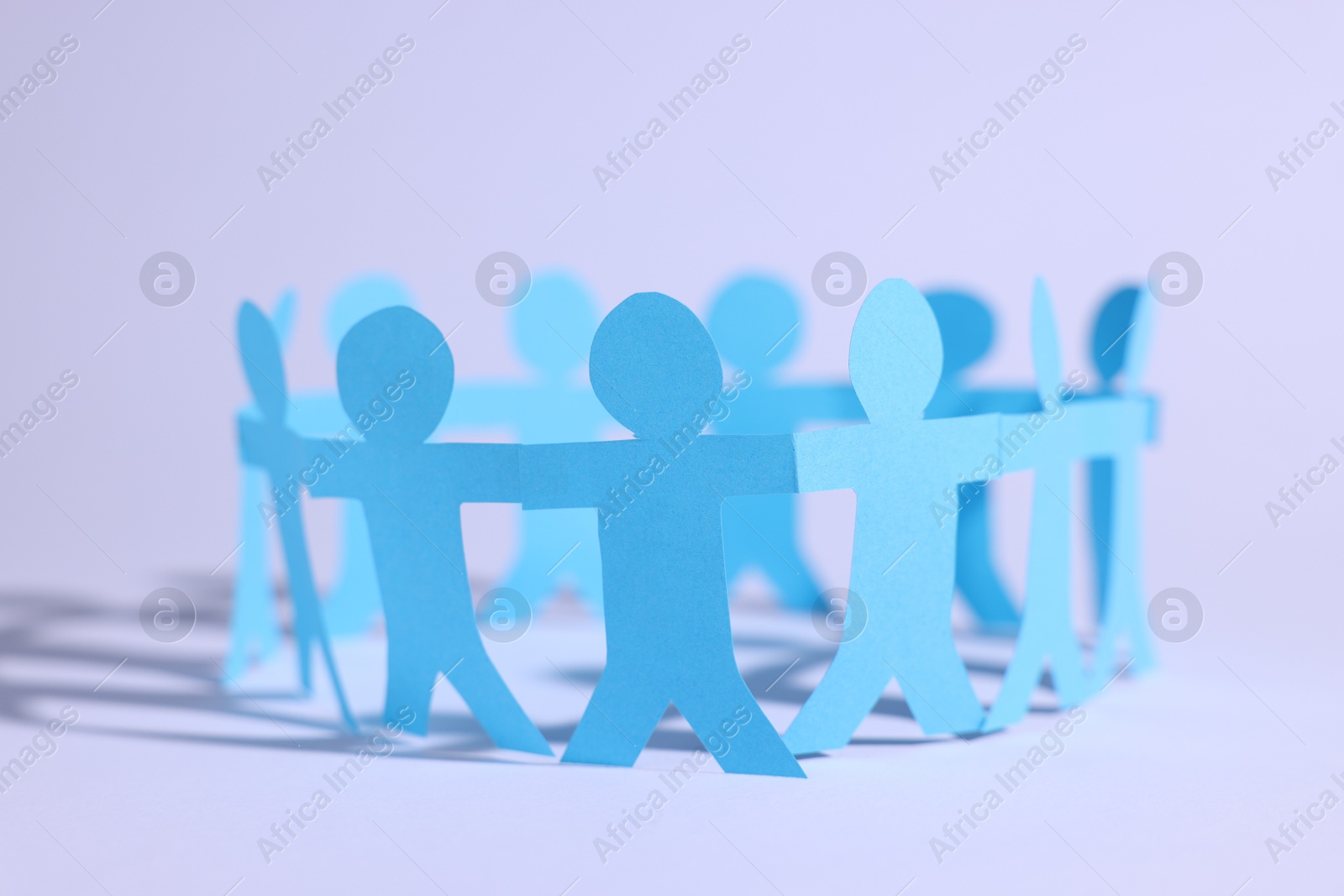 Paper figures of people holding hands on white background, closeup Photo of Paper figures of people holding hands on white background, closeup