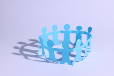 Photo of Paper figures of people holding hands on white background, closeup. Space for text