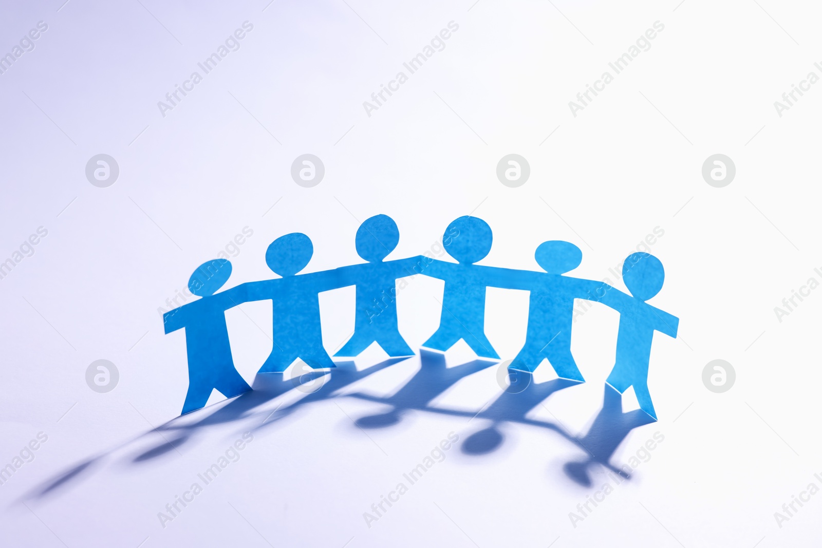 Paper figures of people holding hands on white background Photo of Paper figures of people holding hands on white background