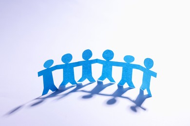 Photo of Paper figures of people holding hands on white background