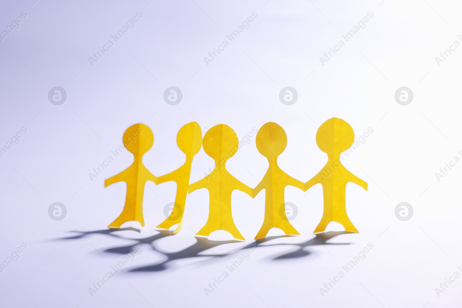 Paper figures of people holding hands on white background Photo of Paper figures of people holding hands on white background