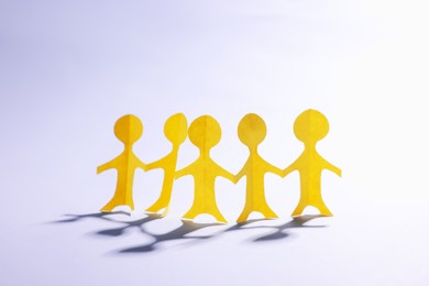 Photo of Paper figures of people holding hands on white background