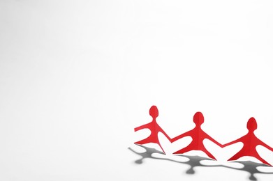Photo of Paper figures of people holding hands on white background, space for text