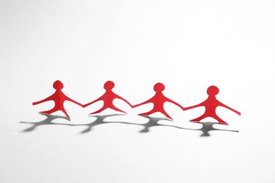 Photo of Paper figures of people holding hands on white background