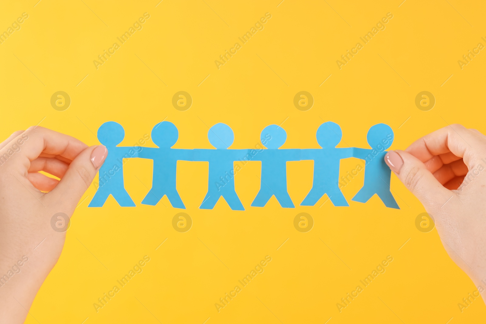 Woman holding paper figures of people on orange background, closeup Photo of Woman holding paper figures of people on orange background, closeup