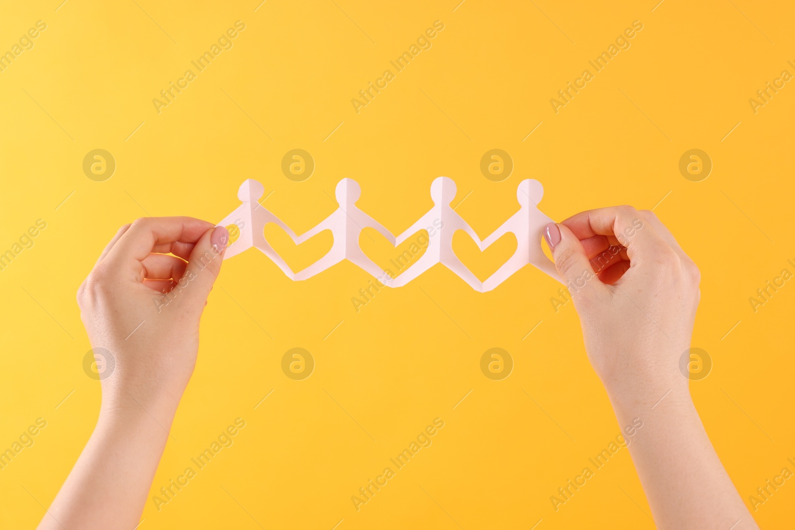 Woman holding paper figures of people on orange background, closeup Photo of Woman holding paper figures of people on orange background, closeup