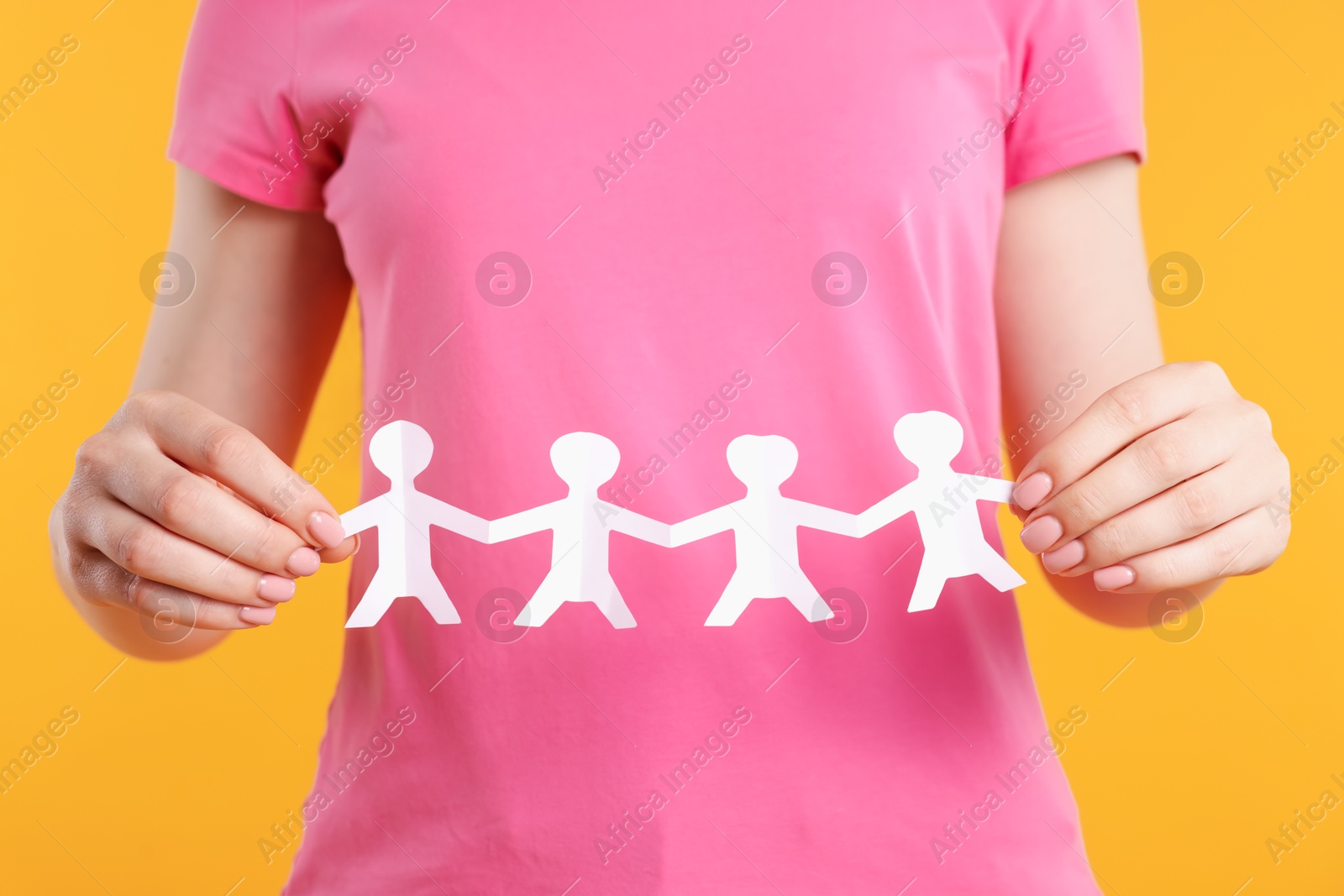 Woman holding paper figures of people on orange background, closeup Photo of Woman holding paper figures of people on orange background, closeup