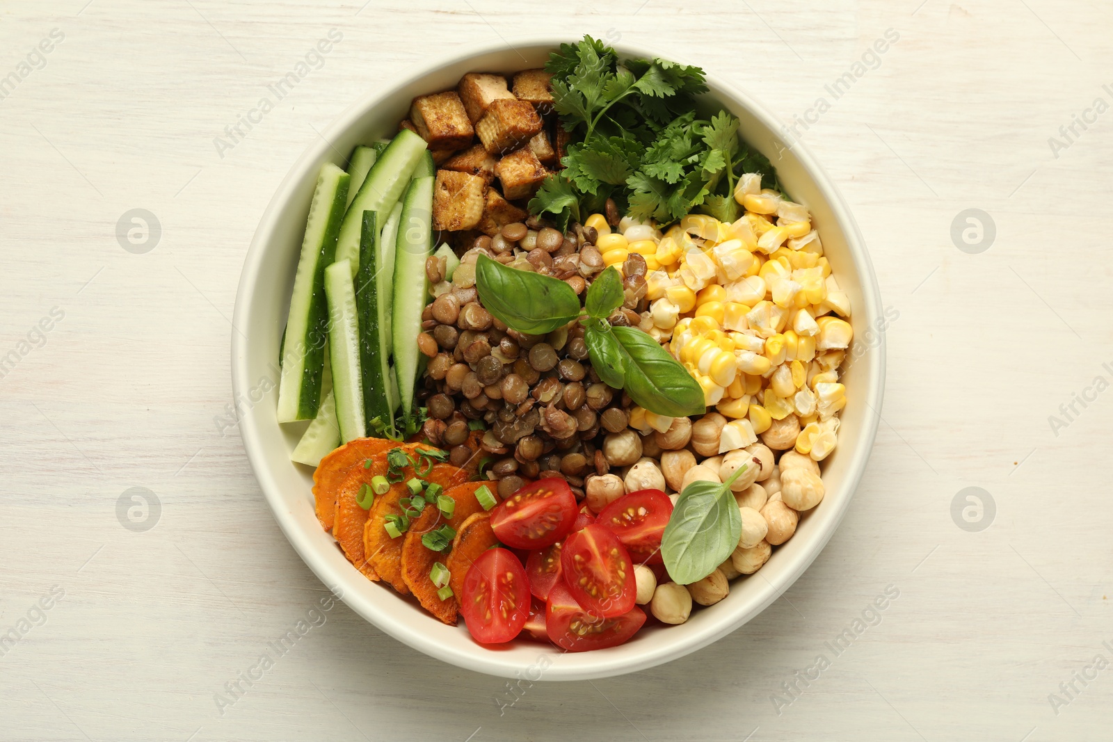Healthy vegetarian food. Delicious Buddha bowl with lentils, tofu, chickpeas and vegetables on light wooden table, top view Photo of Healthy vegetarian food. Delicious Buddha bowl with lentils, tofu, chickpeas and vegetables on light wooden table, top view