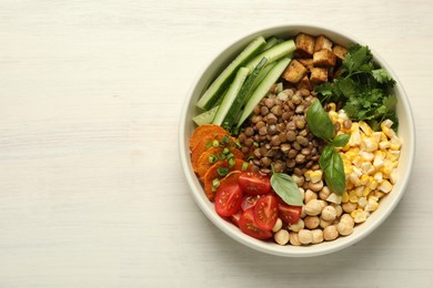 Photo of Healthy vegetarian food. Delicious Buddha bowl with lentils, tofu, chickpeas and vegetables on light wooden table, top view. Space for text