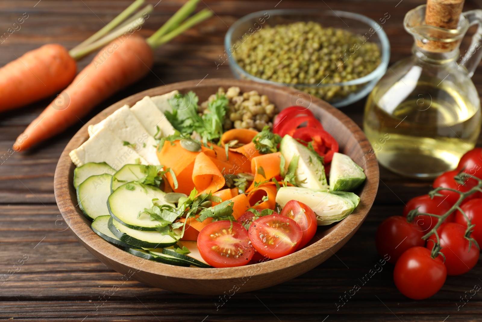 Healthy vegetarian food. Delicious Buddha bowl and ingredients on wooden table, closeup Photo of Healthy vegetarian food. Delicious Buddha bowl and ingredients on wooden table, closeup