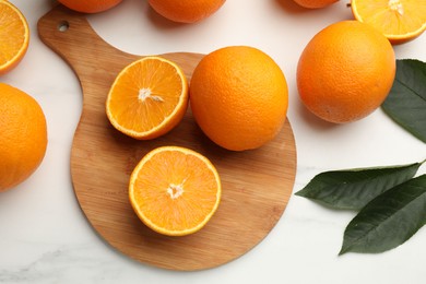 Photo of Fresh oranges and leaves on white table, flat lay