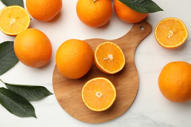 Photo of Fresh oranges and leaves on white table, flat lay