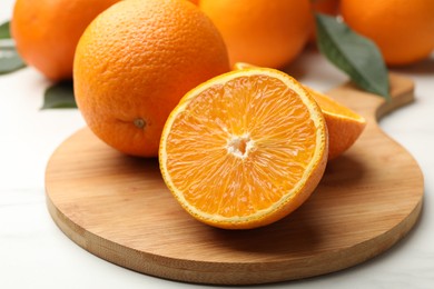 Photo of Whole and cut oranges on white table, closeup