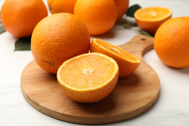 Photo of Whole and cut oranges on white table, closeup