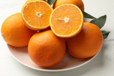 Photo of Whole and cut oranges on white table, closeup