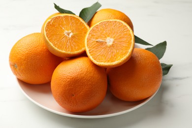 Photo of Whole and cut oranges on white table, closeup