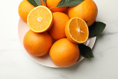 Photo of Fresh oranges and leaves on white table, top view