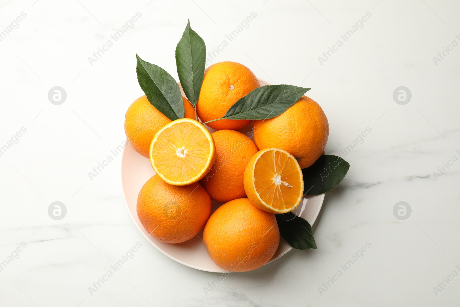 Fresh oranges and leaves on white marble table, top view Photo of Fresh oranges and leaves on white marble table, top view