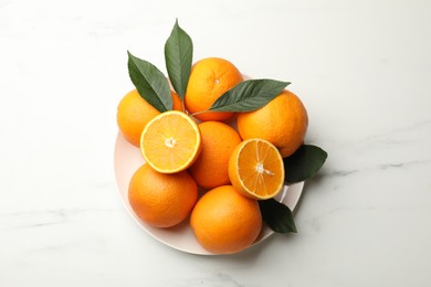 Photo of Fresh oranges and leaves on white marble table, top view