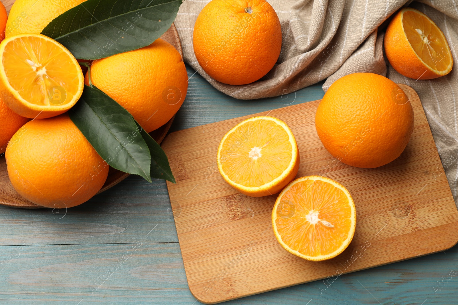Fresh oranges and leaves on light blue wooden table, flat lay Photo of Fresh oranges and leaves on light blue wooden table, flat lay