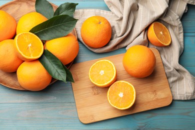 Photo of Fresh oranges and leaves on light blue wooden table, flat lay