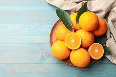 Photo of Fresh oranges and leaves on light blue wooden table, top view. Space for text