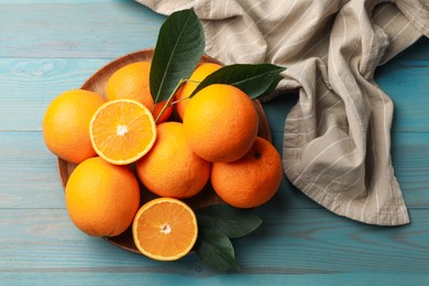Photo of Fresh oranges and leaves on light blue wooden table, top view