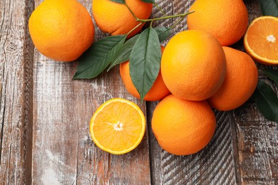 Photo of Fresh oranges and leaves on wooden table, flat lay